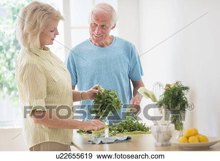 Couple preparing food in kitchen View Large Photo Image Stock Photo - Couple preparing food in kitchen. Fotosearch