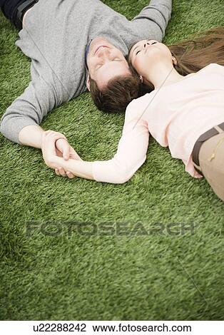 Couple relaxing on grass View Large Photo Image Stock Image - Couple relaxing on grass. Fotosearch