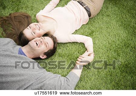 Couple relaxing on grass View Large Photo Image Stock Photo - Couple relaxing on grass. Fotosearch
