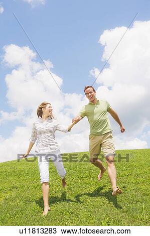 Couple running on grass View Large Photo Image Stock Image - Couple running on grass. Fotosearch