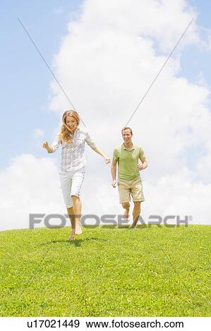 Stock Photo - Couple running on grass. Fotosearch