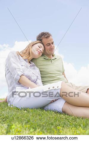 Stock Photograph - Couple sitting on grass. Fotosearch