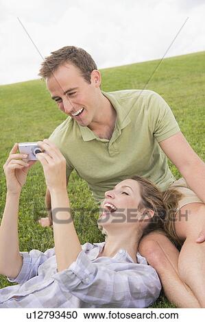 Couple sitting on lawn with camera View Large Photo Image Stock Image - Couple sitting on lawn with camera. Fotosearch