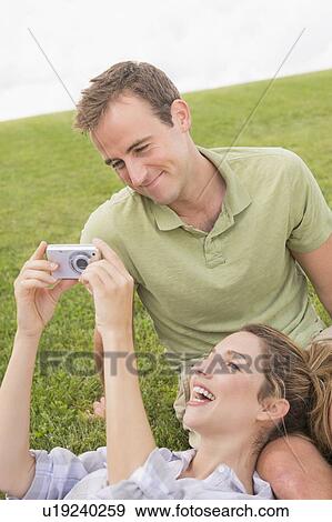 Couple sitting on lawn with camera View Large Photo Image Stock Photo - Couple sitting on lawn with camera. Fotosearch