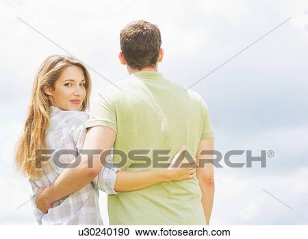 Stock Image - Couple standing on grass and embracing. Fotosearch