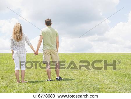 Couple standing on grass and holding hands View Large Photo Image Stock Image - Couple standing on grass and holding hands. Fotosearch