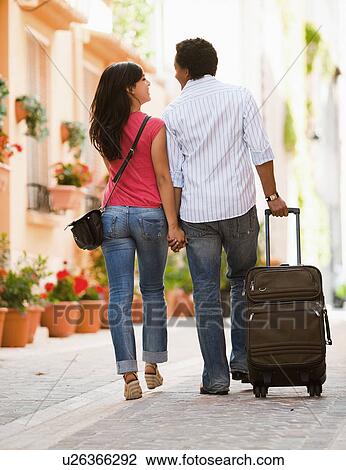 Stock Image - France, Cassis, Couple of tourist walking street with suitcase. Fotosearch