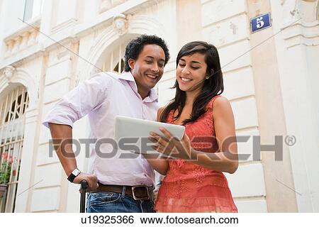 Stock Photograph - France, Cassis, Couple using digital tablet on street. Fotosearch