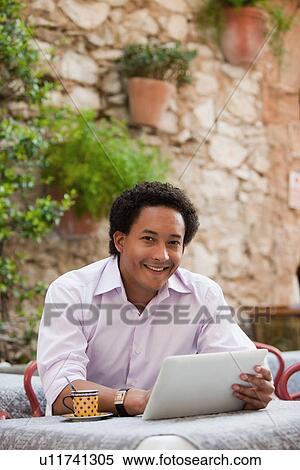 Stock Photography - France, Cassis, Man using digital tablet in cafe. Fotosearch