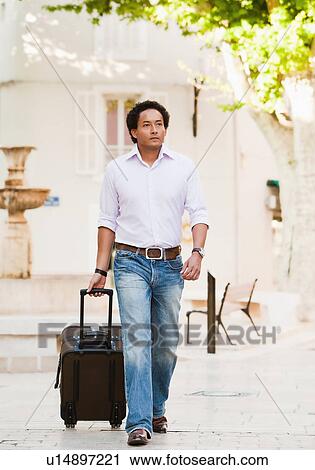 Stock Image - France, Cassis, Man walking with suitcase. Fotosearch