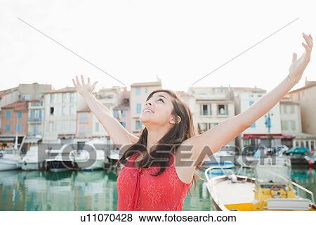 Stock Photo - France, Cassis, Portrait of young woman with arms spread. Fotosearch