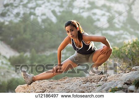 Stock Photo - France, Marseille, Young woman stretching on cliff. Fotosearch