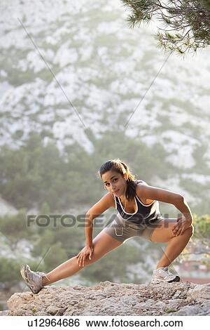 Stock Photograph - France, Marseille, Young woman stretching on cliff. Fotosearch