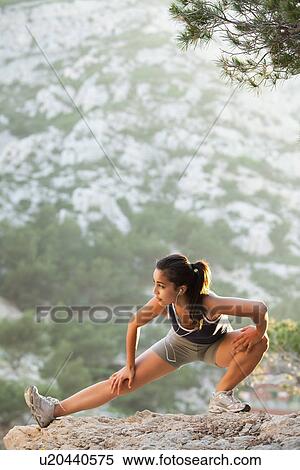 Stock Photography - France, Marseille, Young woman stretching on cliff. Fotosearch