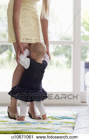 Girl hiding in mother's legs View Large Photo Image Stock Image - Girl hiding in mother's legs. Fotosearch