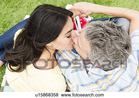 Happy couple kissing on grass View Large Photo Image Stock Photo - Happy couple kissing on grass. Fotosearch