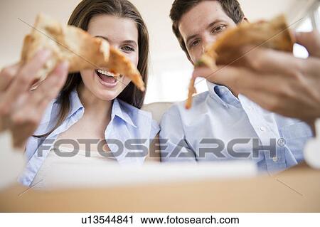 Stock Image - Happy young couple eating pizza. Fotosearch