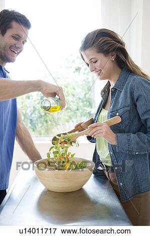 Stock Photo - Happy young couple making salad. Fotosearch