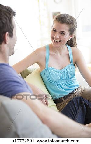 Happy young couple sitting together on sofa View Large Photo Image Stock Image - Happy young couple sitting together on sofa. Fotosearch
