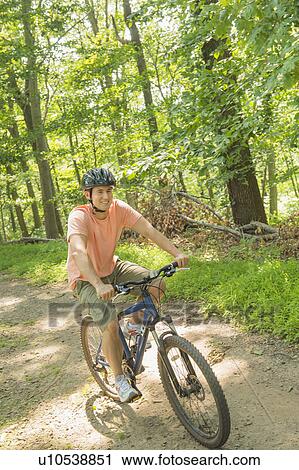 Stock Image - Man cycling in forest. Fotosearch