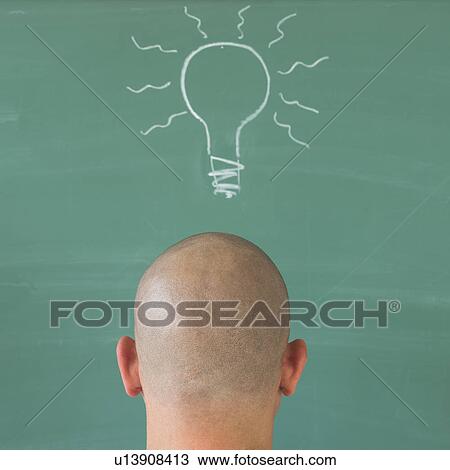 Stock Image - Man in front of blackboard with drawing depicting Lightbulb. Fotosearch