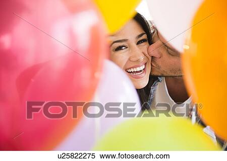 Man kissing woman behind colorful balloons View Large Photo Image Stock Photography - Man kissing woman behind colorful balloons. Fotosearch