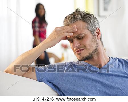 Man touching forehead, woman in background View Large Photo Image Stock Photograph - Man touching forehead, woman in background. Fotosearch
