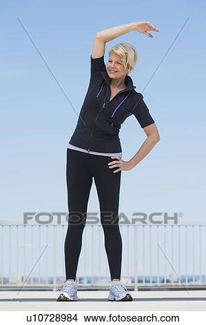 Picture - Mature woman exercising outdoors. Fotosearch