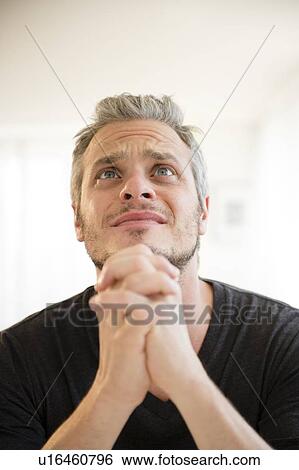 Stock Photograph - Mid adult man in praying gesture. Fotosearch