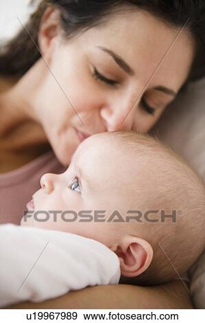 Stock Photo - Mother and baby boy (2-5 months) lying together on bed. Fotosearch