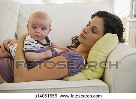 Stock Photograph - Mother and baby boy (2-5 months) lying together on sofa. Fotosearch