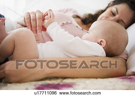 Mother and baby boy (2-5 months) lying together on bed View Large Photo Image Stock Photograph - Mother and baby boy (2-5 months) lying together on bed. Fotosearch