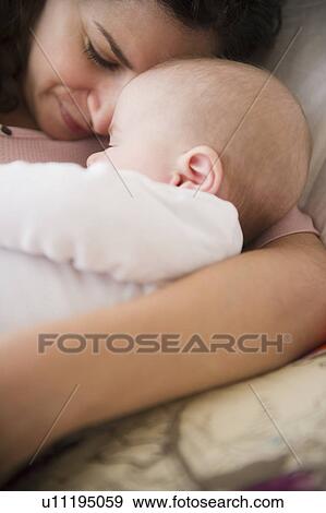 Stock Photo - Mother and baby boy (2-5 months) sleeping together . Fotosearch