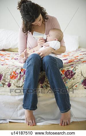 Stock Image - Mother feeding baby boy (2-5 months) using feeding bottle. Fotosearch