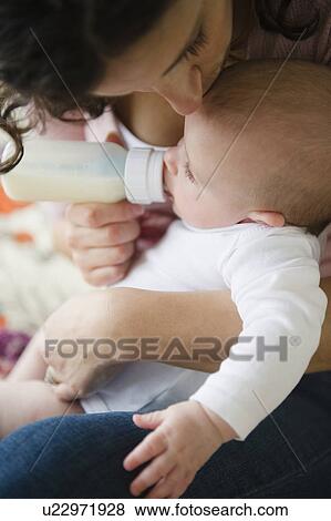 Stock Photo - Mother feeding baby boy (2-5 months) using feeding bottle. Fotosearch