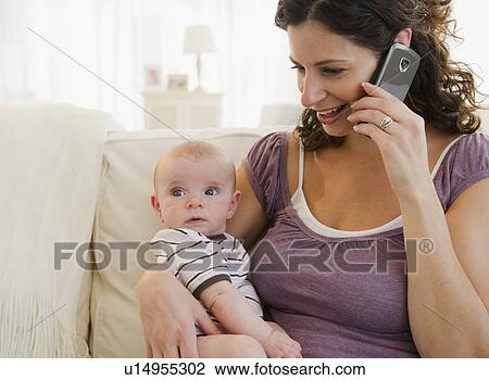 Stock Image - Mother with baby boy (2-5 months) using mobile phone. Fotosearch
