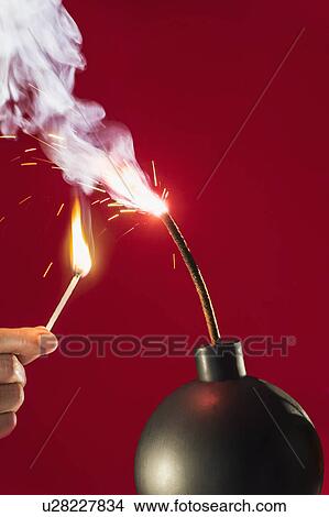 Old-fashioned explosive device ready to go off with hand holding burning match View Large Photo Image Picture - Old-fashioned explosive device ready to go off with hand holding burning match. Fotosearch