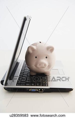 Stock Image - Piggybank sitting in open laptop. Fotosearch