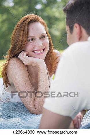 Stock Image - Portrait of couple lying on blanket and smiling. Fotosearch
