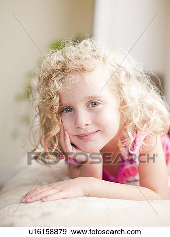 Portrait of girl (4-5) lying on bed View Large Photo Image Stock Photo - Portrait of girl (4-5) lying on bed. Fotosearch