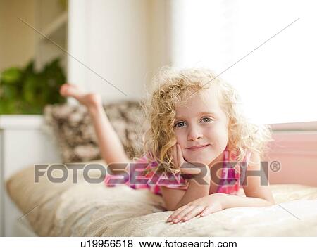 Stock Photo - Portrait of girl (4-5) lying on bed. Fotosearch