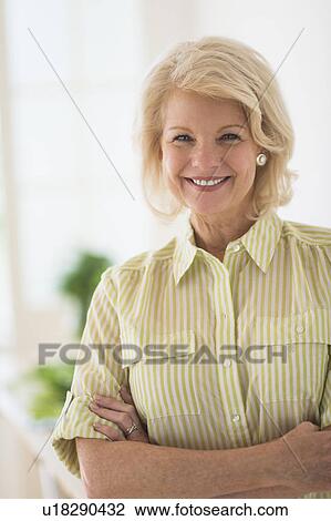 Stock Image - Portrait of mature woman in kitchen. Fotosearch