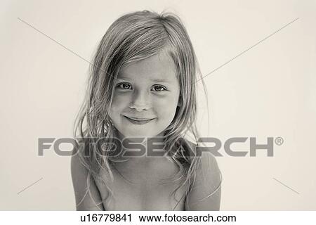 Stock Image - Portrait of smiling girl (6-7), studio shot. Fotosearch