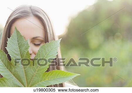 Stock Photography - Portrait of woman holding green leaf. Fotosearch