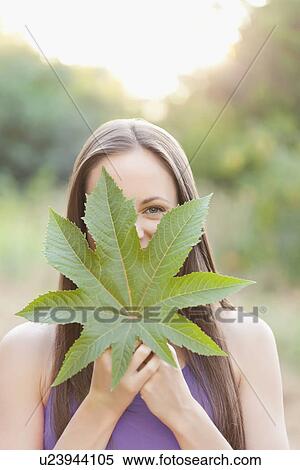 Stock Photography - Portrait of woman holding green leaf. Fotosearch