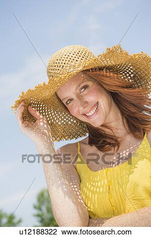 Stock Image - Portrait of woman wearing straw hat. Fotosearch