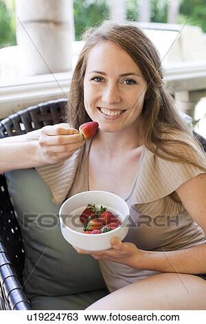 Stock Image - Portrait of young woman having strawberry. Fotosearch
