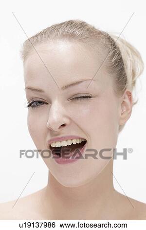Stock Photograph - Portrait of young woman laughing and making eye. Fotosearch