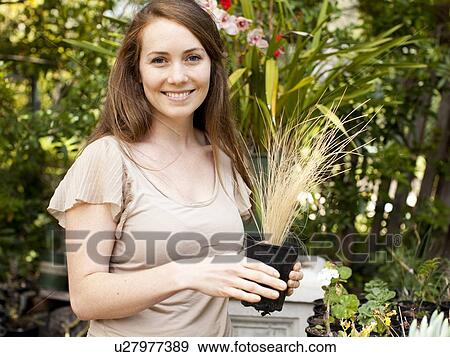 Portrait of young woman with flower in pot View Large Photo Image Stock Photo - Portrait of young woman with flower in pot. Fotosearch