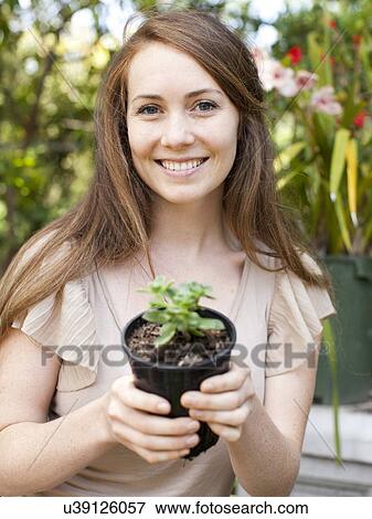 Portrait of young woman with flower in pot View Large Photo Image Stock Photo - Portrait of young woman with flower in pot. Fotosearch